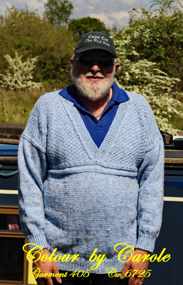 A V neck jumper hand knitted aboard the narrow boat “Emma Maye” in Lancashire by Carole Wareing of Colin and Carole’s Creations. Modelled by Colin, Carole’s husband, it’s a bit tight on him! This garment has been designed and knitted by Carole. It has been created from a shade of “Misty” from J C Brett’s (shade no R5) which is a premium acrylic yarn with a touch of viscose to make it feel nice and soft. The garment is based on a “Scarborough” gansey pattern which has a moss stitch above the yoke on the chest area, while there is a quite distinctive step stitch border between the main body and the arms.