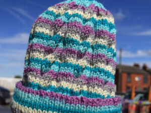 Purple Rain wool hat A multi coloured ribbed hat hand knitted by Carole on the Wool Boat from the West Yorkshire Spinners “Colour Lab” range.