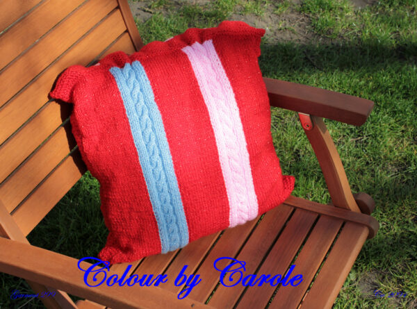 A bright red twinkly cushion cover with contrasting stripes designed and hand knitted by Carole The cushion cover 15inches by 15 inches square, with two cabled panels with 6 buttons to close the access flap, you need to provide your own cushion! Knitted from “Twinkle” an acrylic yarn which is available in a wide range of vibrant colours so the cushion can be reproduced in various shades and colour combinations to suit you decor scheme, please feel free to get in touch with your requirements.