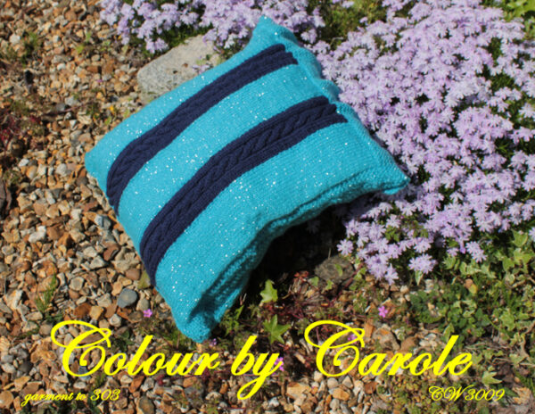 A cushion cover designed and hand knitted by Carole Wareing of Colin and Carole’s Creations and The Wool Boat. The cushion cover 15inches by 15 inches square, with two cabled panels with 6 buttons to close the access flap.