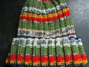 Fairground hat in red, yellow and green shades. A striped hat hand knitted aboard the narrow boat “Emma Maye” in Lancashire by Carole Wareing of Colin and Carole’s Creations. Great for an adult or teenager, Colour – red, yellow and green shades in horizontal stripes of varying depths. Machine washable at 30 degrees C The price is £10 or £13 including delivery to a uk address Created from a shade G14 from J C Brett’s “Fairground” range which we stock on The Wool Boat. Hand knitted by Carole Wareing Garment 652 Cw 8502