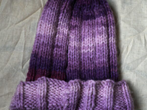 Chunky Aurora ribbed hat in shades of purple. A chunky ribbed beanie style hat hand knitted aboard the narrow boat “Emma Maye” in Lancashire by Carole Wareing of Colin and Carole’s Creations. Great for an adult or teenager, Colour – shades of purple in horizontal stripes of varying depths.