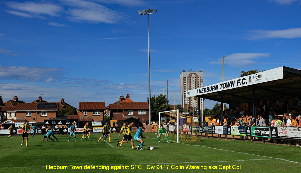  Hebburn Town defending against SFC

Hebburn Town F C are defending their goal against a Southport F C attack on Saturday the 8.8.2026 in the first game Hebburn have played in the National League North. 
Hebburn had won promotion from the Northern Premier league at the end of last season, to the highest league they have played in in the English football pyramid. 
They went on to make a winning start to life at this level winning this game 3-1.
Hebburn are the team in the yellow and black shirts while Southport are in their away kit of blue.
This scene is due to change in the next few years with the planned demolition of the tall block of flats behind the ground.
Image Cw 9447 copyright Colin Wareing of Colin and Carole’s Creation